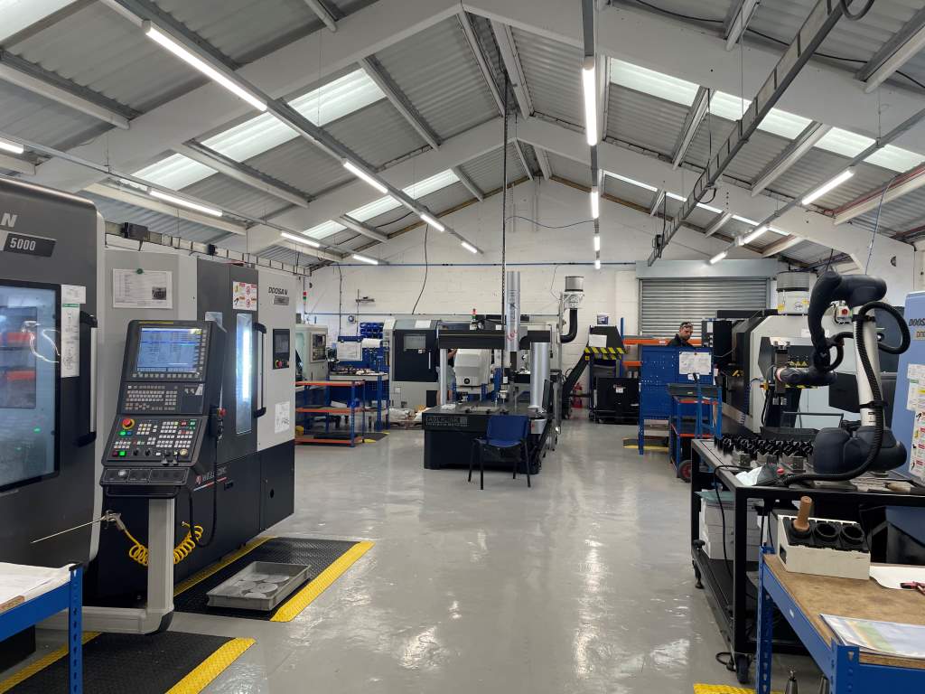 The shopfloor at ASG Arrowsmith. DVF 5000 simultaneous 5-axis machining centre integrated with an eight-station automatic workpiece pallet changer on the left; cobot cell on the right